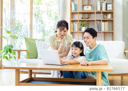 リビングでパソコンを見る若い家族 92766577