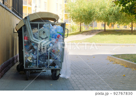 Plastic bottles are collected in a container for sending for recycling. Dumpsters being full with garbage in city. 92767830