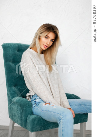 Portrait of pretty blonde woman sits on a chair. Studio shot Portrait of pretty blonde woman sits on a chair. Studio shot 92768397