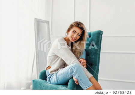 Portrait of pretty blonde woman sits on a chair. Studio shot Portrait of pretty blonde woman sits on a chair. Studio shot 92768428
