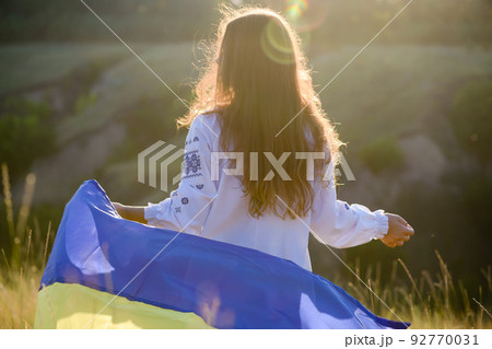 A beautiful teenage girl dressed in national clothes waving the Ukrainian flag 92770031