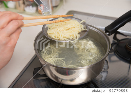 【ミドル主婦がラーメンの麺を菜箸と笊を使って茹でる】 92770398