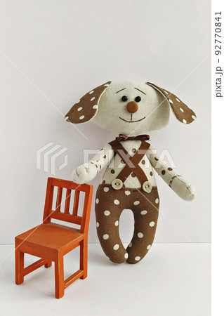 Funny toy fabric dog with polka dots with miniature chair on white background by handmade. Decorative soft toy, DIY Funny toy fabric dog with polka dots with miniature chair on white background by handmade. Decorative soft toy, DIY 92770841