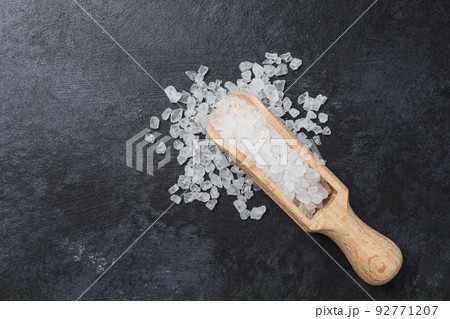 Sea salt in wooden bowl on black table. 92771207