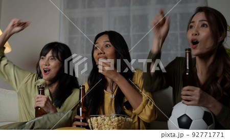 Holiday concept of 4k Resolution. A group of Asian women watching a soccer match broadcast together at home. Fun and exciting leisure activities. Holiday concept of 4k Resolution. A group of Asian women watching a soccer match broadcast together at home. Fun and exciting leisure activities. 92771771