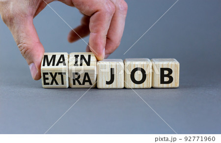 Extra or main job symbol. Businessman turns wooden cubes and changes concept words Extra job to Main job. Beautiful grey table grey background, copy space. Business extra or main job concept. Extra or main job symbol. Businessman turns wooden cubes and changes concept words Extra job to Main job. Beautiful grey table grey background, copy space. Business extra or main job concept. 92771960