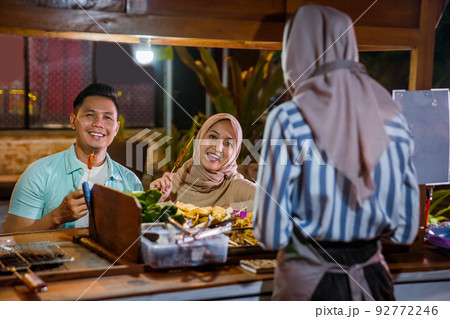 muslim couple enjoying having dinner out at traditional food market 92772246