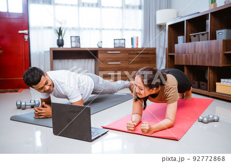 Asian fitness couple planking and looking at online video tutorial Asian fitness couple planking and looking at online video tutorial 92772868