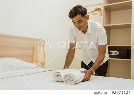 Young asian cleaning boy putting towel on hotel room bed Young asian cleaning boy putting towel on hotel room bed 92773124