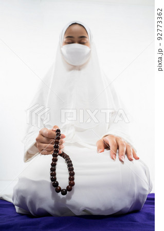 Woman wearing mukena praying with prayer beads on isolated background 92773362