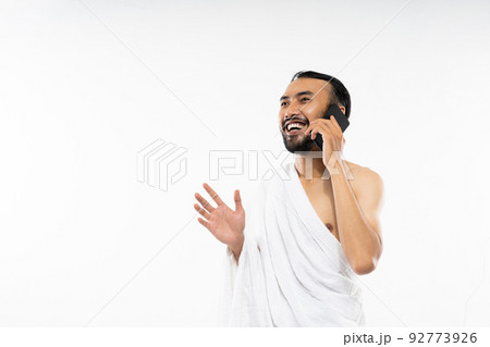 Man wearing ihram clothes using cellphone to make calls Man wearing ihram clothes using cellphone to make calls 92773926