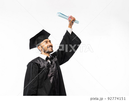 Happy graduates in black togas holding up certificate paper Happy graduates in black togas holding up certificate paper 92774151