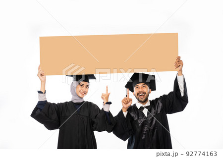 Asian couple of graduate student wearing toga holding cardboard Asian couple of graduate student wearing toga holding cardboard 92774163