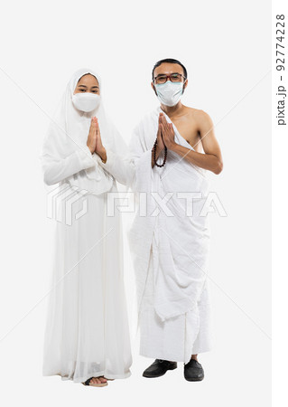 Couple wearing hajj ihram clothes and masks with greeting gesture Couple wearing hajj ihram clothes and masks with greeting gesture 92774228