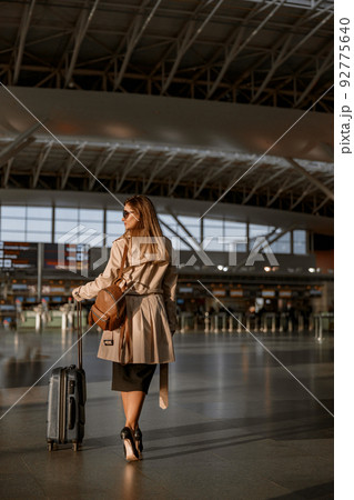 Lady with suitcase and passport walking in arrival or departure hall 92775640