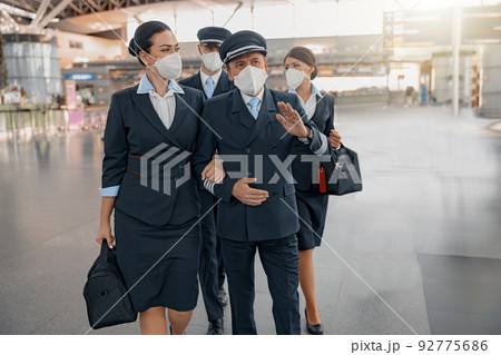 Male pilots and female flight attendants walking in airport terminal together 92775686