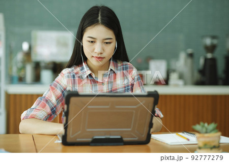 Young asian woman study in front of the laptop computer and and using headphones at offsite.. Young asian woman study in front of the laptop computer and and using headphones at offsite.. 92777279