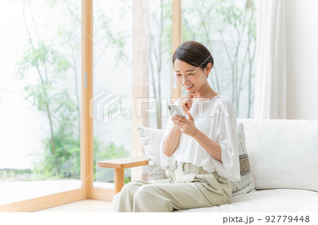 リビングでスマホを使うミドル女性 リビングでスマホを使うミドル女性 92779448
