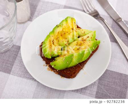 Sandwich with black bread, sliced avocado and sesame Sandwich with black bread, sliced avocado and sesame 92782236