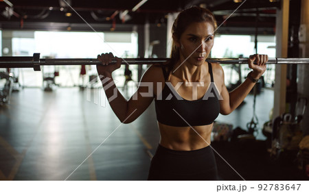 Sporty woman exercising with barbell in fitness class. Workout woman in gym with barbell. Sporty woman exercising with barbell in fitness class. Workout woman in gym with barbell. 92783647