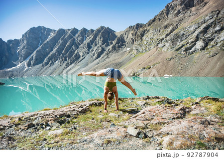 Girl doing yoga near wonderful mountain landscape, lake, highland, peak, beauty world. Picturesque view near Alakul lake. 92787904