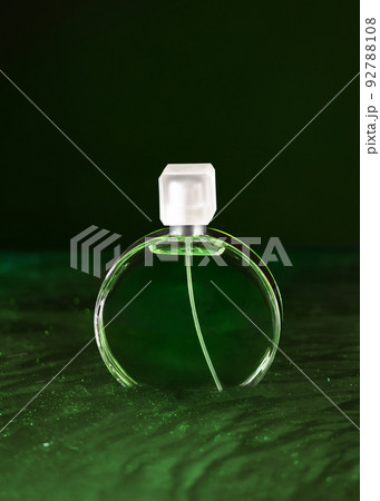 Green bottle of French perfume in green water. Fresh perfume on wavy water. 92788108