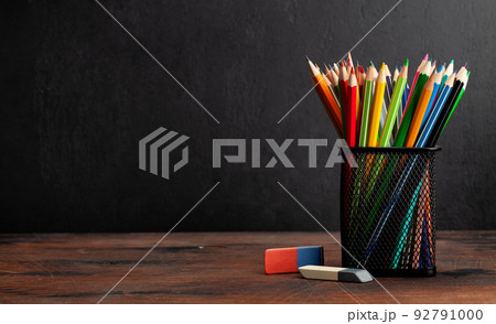 Colorful pencils on wooden table and blackboard 92791000