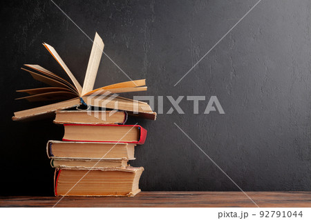 Old books on wooden table and blackboard 92791044