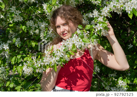 Portrait of beautiful young woman in apple trees blooming park on a sunny day. Springtime 92792525