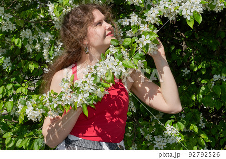 Portrait of beautiful young woman in apple trees blooming park on a sunny day. Springtime 92792526
