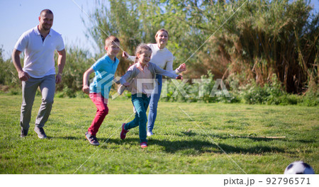 Children and parents run to the soccer sword in the summer in the park Children and parents run to the soccer sword in the summer in the park 92796571