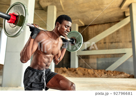 Athletic black young man lifting a heavy-weight barbell in outdoor gym under the bridge. Healthy lifestyle concept 92796681