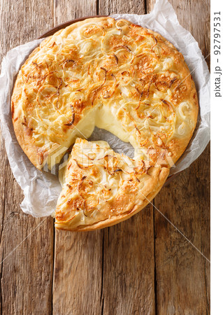 Fugazzeta or fugazza con queso a classic pizza is made with double cream cheese, mozzarella cheese, onion and olive oil closeup in the plate. Vertical top view 92797531