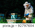 Beekeeper working collect honey. Beekeeping concept. Farmer wearing bee suit working with honeycomb in apiary. Organic farming. Copy-space. 92797604
