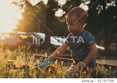 Kid playing with toys outside. Child having fun on playground in sunset. Outdoor creative activities Kid playing with toys outside. Child having fun on playground in sunset. Outdoor creative activities 92797706