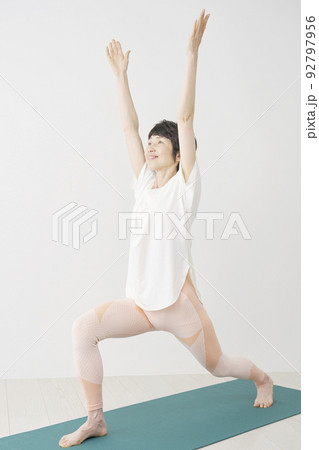 ヨガのハイランジのポーズを自宅でするシニア女性 92797956