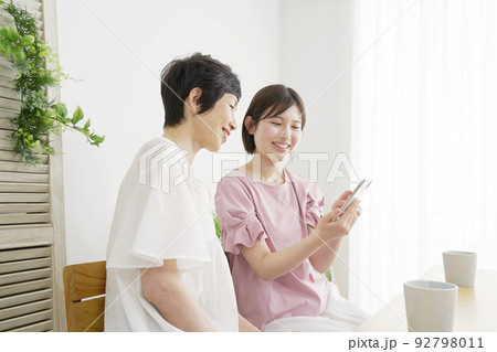 自宅でスマホを使う母親と娘 自宅でスマホを使う母親と娘 92798011