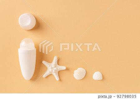 Open roll on antiperspirant deodorant, sea star and shells against pastel orange background. Open roll on antiperspirant deodorant, sea star and shells against pastel orange background. 92798035