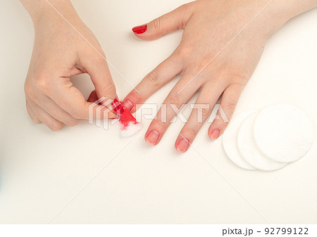 Young woman removes nail polish from her nails with a cotton pad soaked in nail polish remover. 92799122