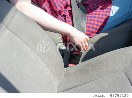 Woman's hand fastens the seat belt of the car for safety before driving on the road. 92799126