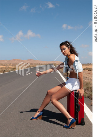 attractive woman hitchhiking on a lonely road 92801627