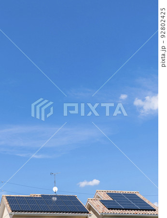 【環境イメージ】太陽光パネルが設置された住宅の屋根と快晴の青空。 92802425