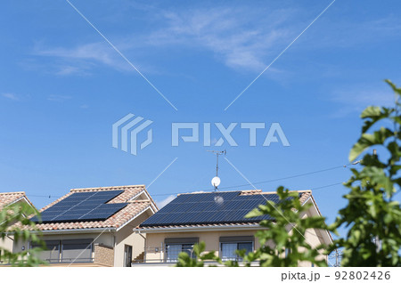 【環境イメージ】太陽光パネルが設置された住宅の屋根と快晴の青空。 92802426