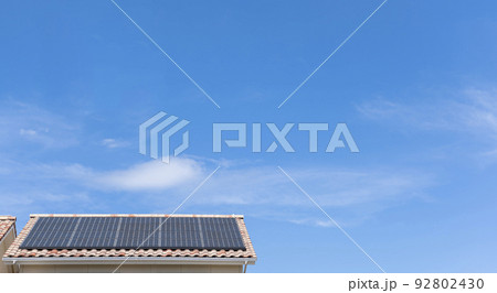【環境イメージ】太陽光パネルが設置された住宅の屋根と快晴の青空。 92802430