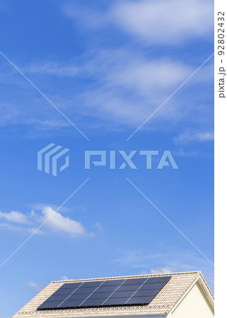 【環境イメージ】太陽光パネルが設置された住宅の屋根と快晴の青空。 92802432