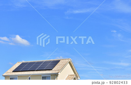 【環境イメージ】太陽光パネルが設置された住宅の屋根と快晴の青空。 92802433