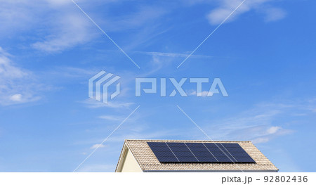 【環境イメージ】太陽光パネルが設置された住宅の屋根と快晴の青空。 92802436