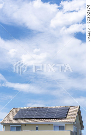 【環境イメージ】太陽光パネルが設置された住宅の屋根と快晴の青空。 92802874
