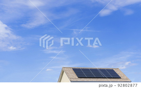 【環境イメージ】太陽光パネルが設置された住宅の屋根と快晴の青空。 92802877