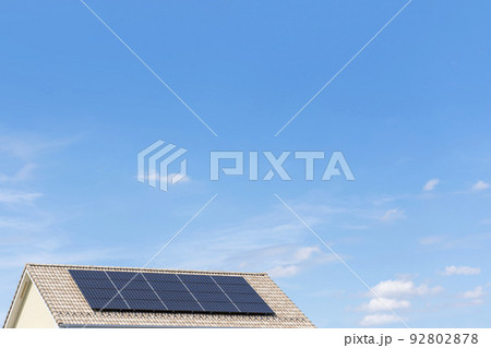【環境イメージ】太陽光パネルが設置された住宅の屋根と快晴の青空。 92802878